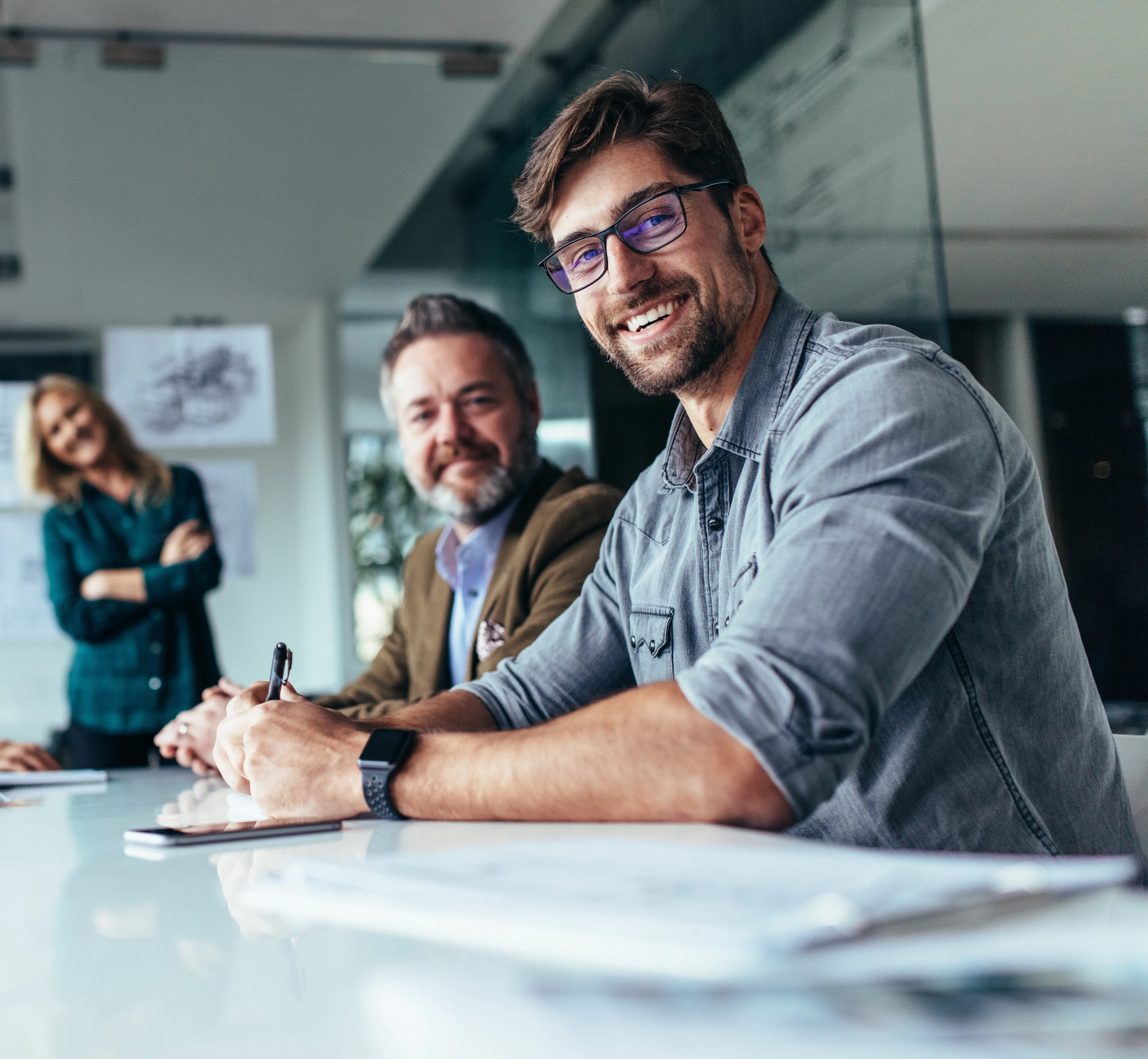 Smiling workers sitting at a conference table in an office.